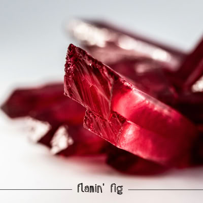 Close-up of red crystalline structures with sharp edges on a light background, with text "Flamin' Fig" at the bottom.